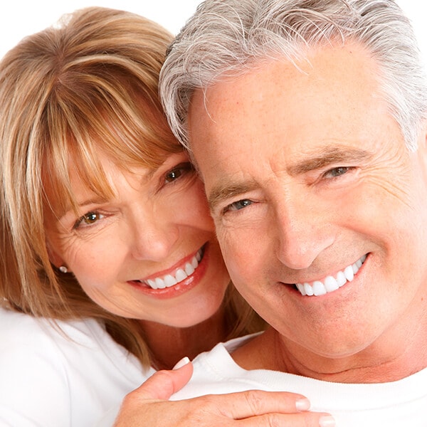 A mature couple hugging each other and smiling with white dentures