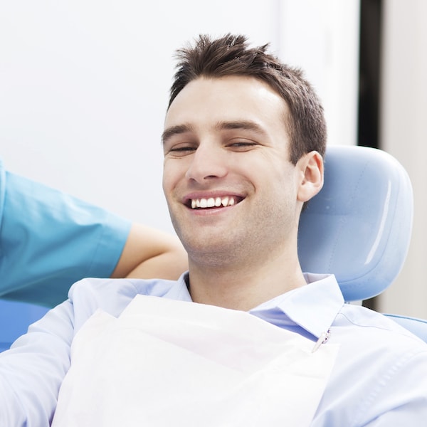 Young man sitting in a blue dental treatment chair visiting his dentist for restorative treatment