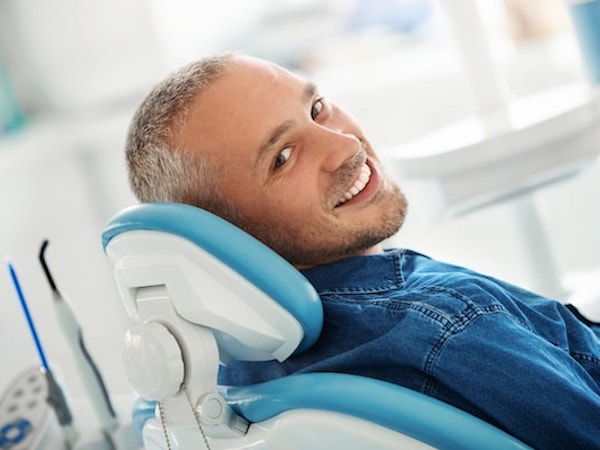 Man in a denim shirt reclining in a dental chair
