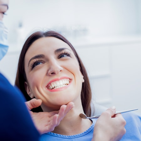 A close up of a woman in a dental chair receiving an oral cancer screening