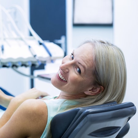 Woman laying on a dental treatment chair as she waits to receive a root canal