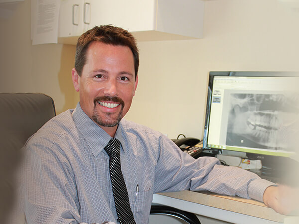 Our Bonney Lake Family Dentist, Dr. Brent Romberg, smiling at his desk